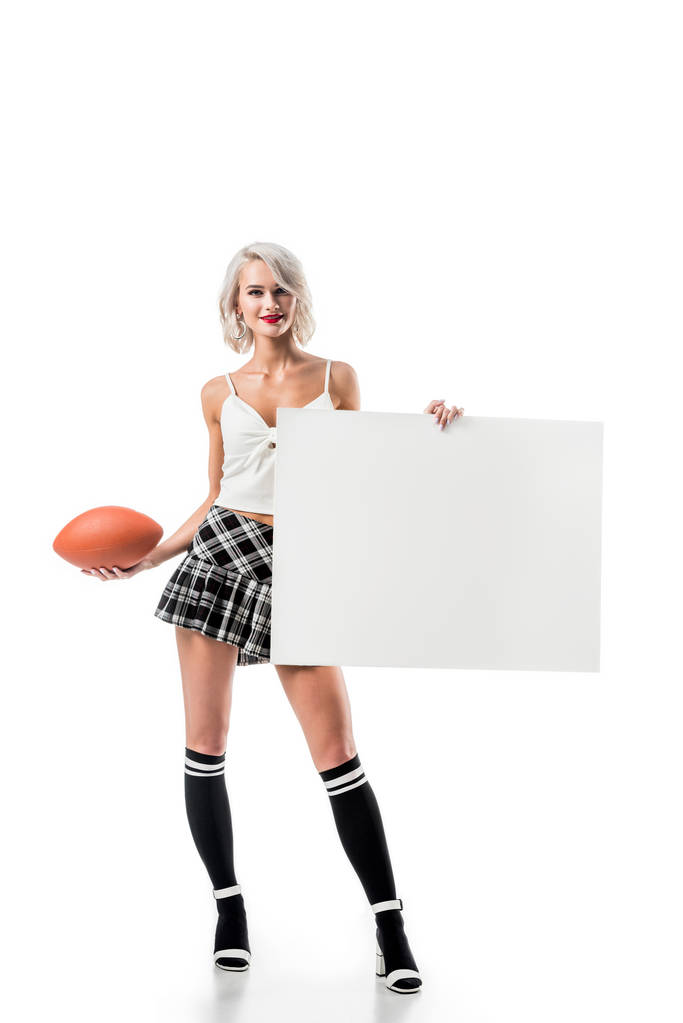 sexy blond woman in short plaid skirt with rugby ball and empty banner posing isolated on white - Photo, Image