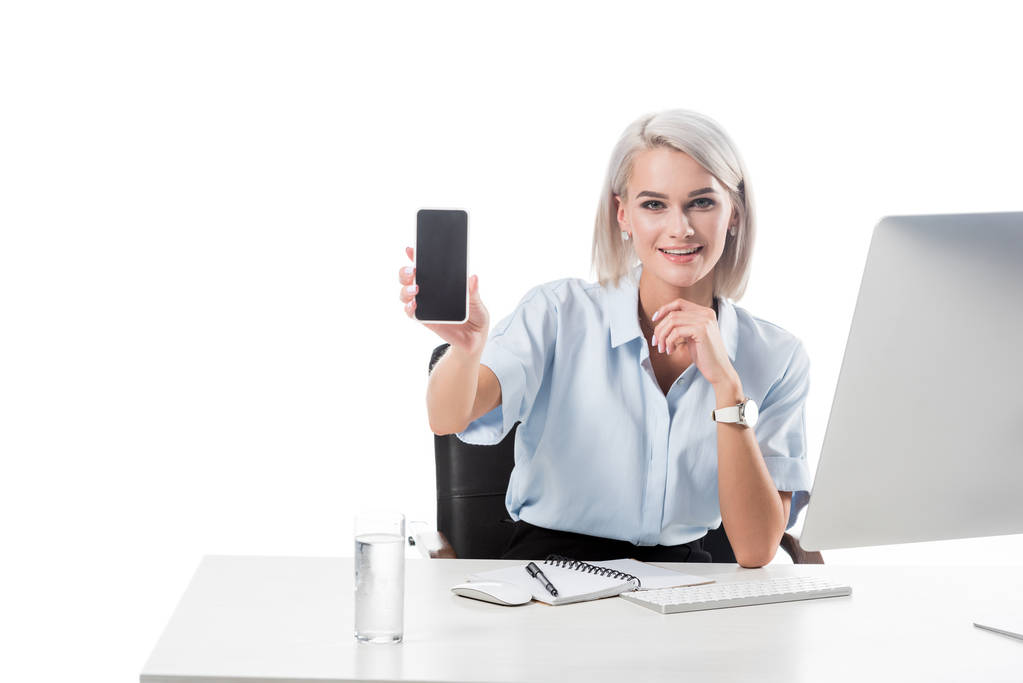 retrato de una mujer de negocios sonriente mostrando un teléfono inteligente con pantalla en blanco en el lugar de trabajo aislado en blanco
 - Foto, imagen