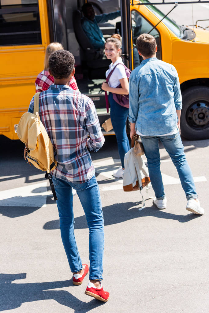 vista trasera del grupo de adolescentes eruditos caminando al autobús escolar después de la escuela
 - Foto, imagen