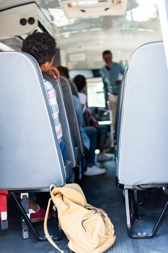 Dikiz okul otobüsü oturma ve öğretmen için dinleme genç öğrenciler - Fotoğraf, Görsel