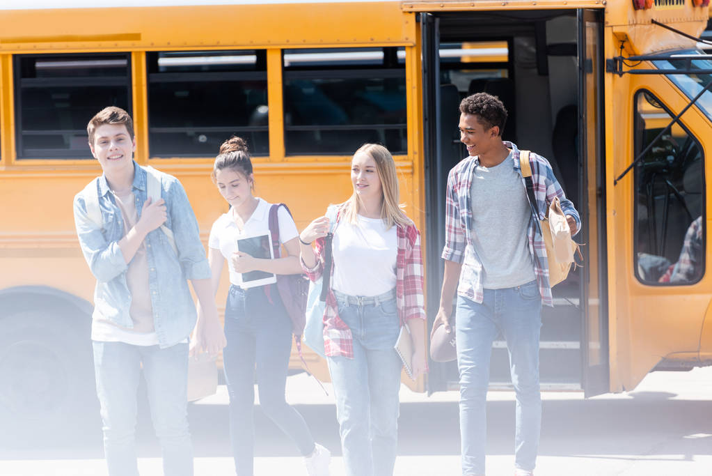 grupo de adolescentes eruditos caminando juntos frente al autobús escolar
 - Foto, imagen