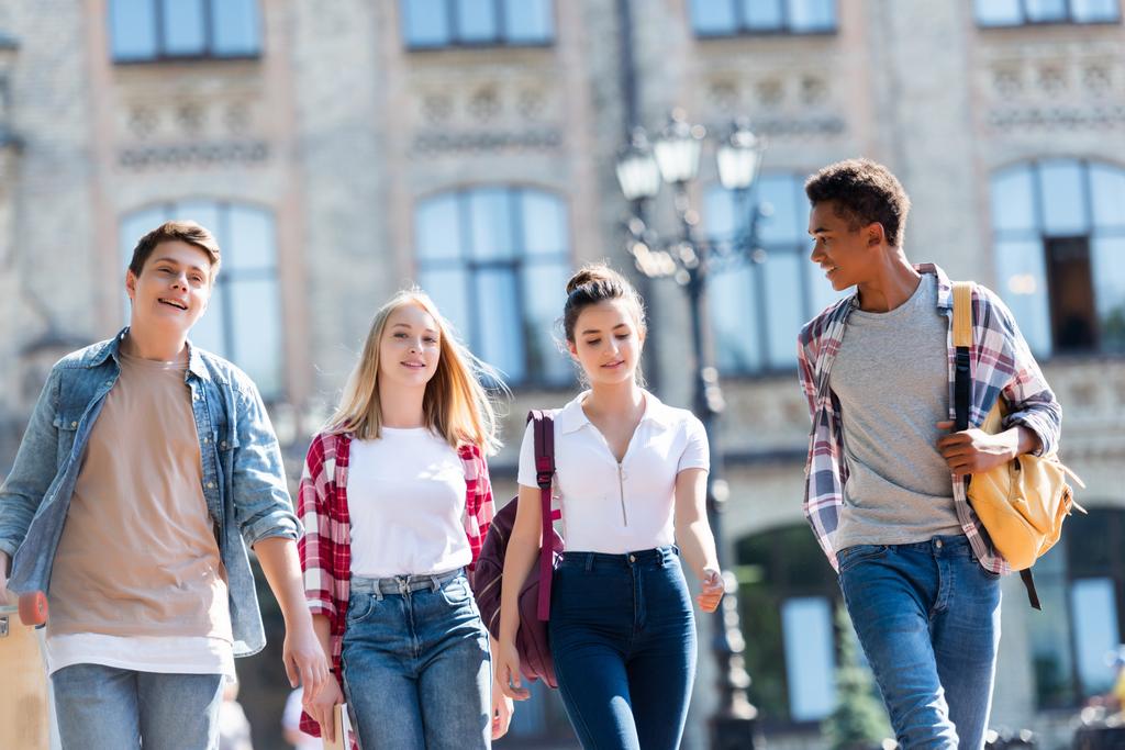 группа счастливых мультиэтнических подростков с рюкзаками, гуляющих вместе
 - Фото, изображение