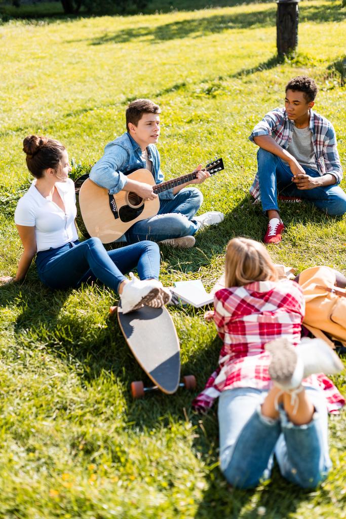 Grupa nastolatków spędzać czas razem i słuchając piosenki gitarowe - Zdjęcie, obraz