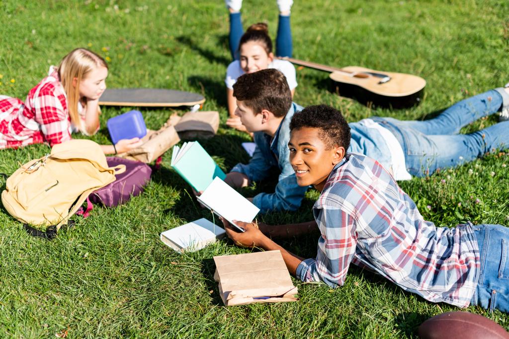 grupo de feliz adolescente estudiosos deitado na grama e estudando juntos
 - Fotografia, imagem