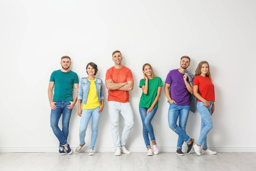 Ryhmä nuoria farkuissa ja värikkäissä t-paidoissa lähellä valoseinää
 - Valokuva, kuva