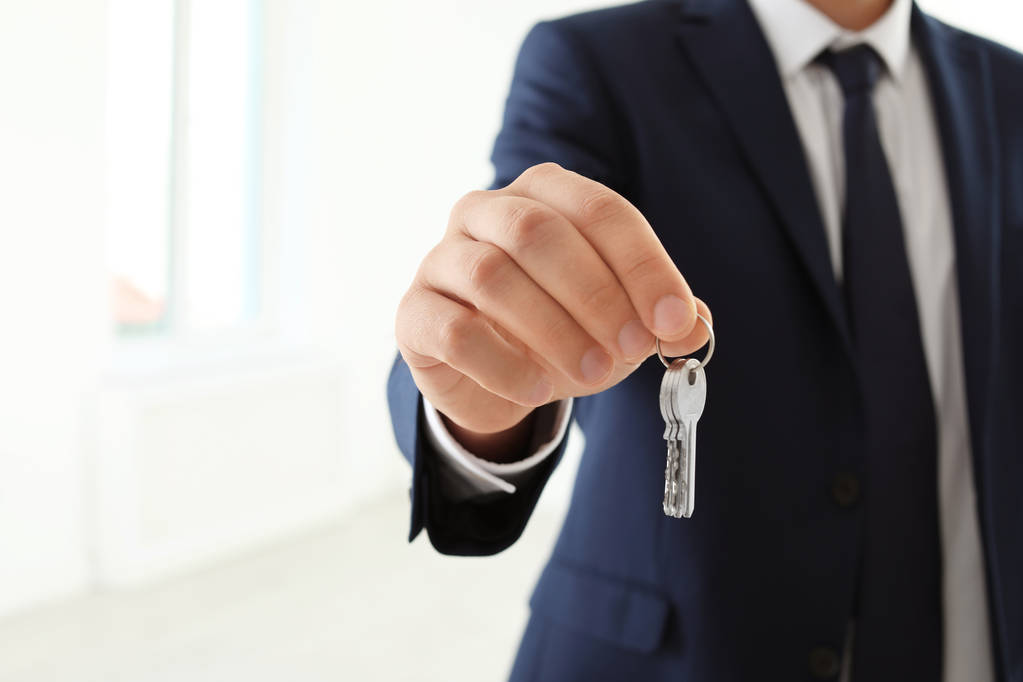 Realitní agent drží klíče na rozmazané pozadí, closeup - Fotografie, Obrázek