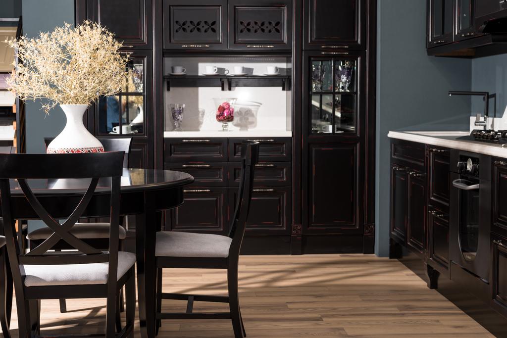 інтер'єр сучасної їдальні з чорними меблями і вазою сухоцвітів на столі
 - Фото, зображення
