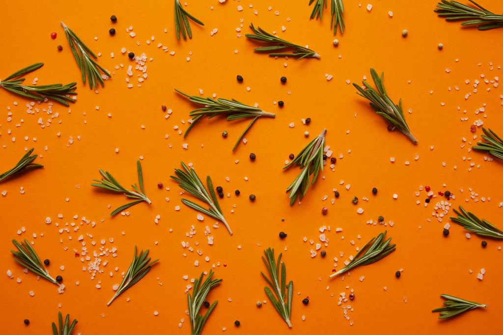 vista superior de romero, sal y granos de pimienta sobre fondo naranja
 - Foto, imagen