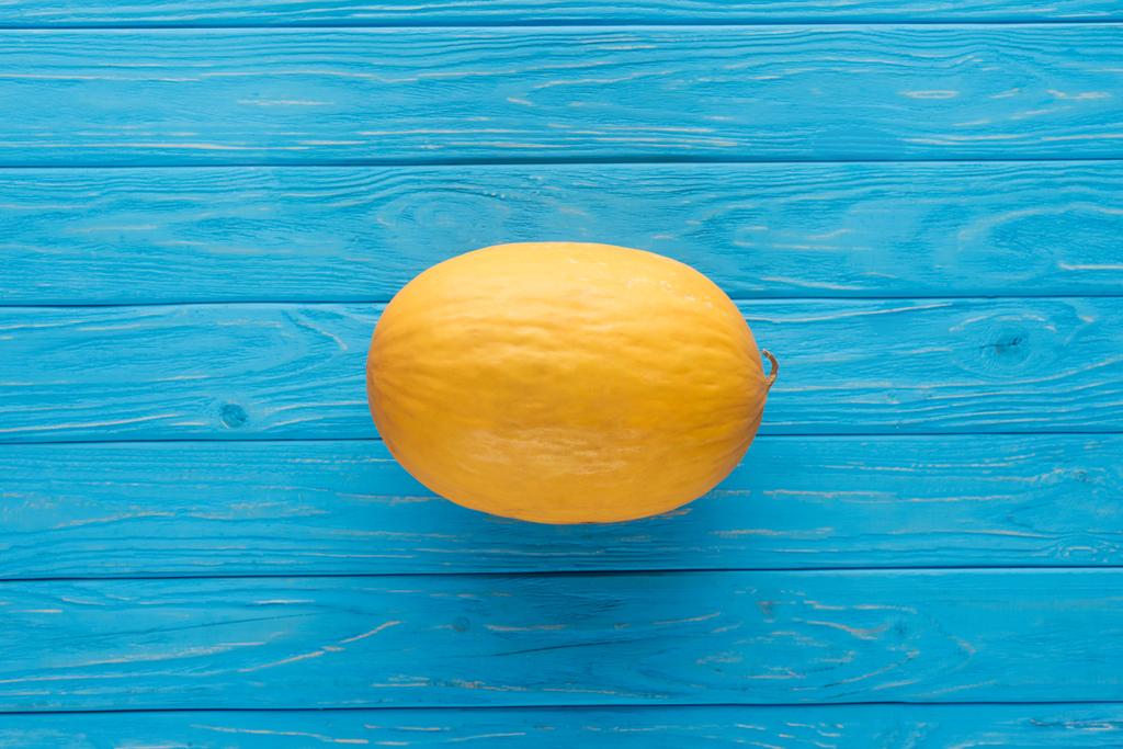 Widok z góry z całego dojrzałego melona żółtego na niebieski powierzchni drewnianych   - Zdjęcie, obraz