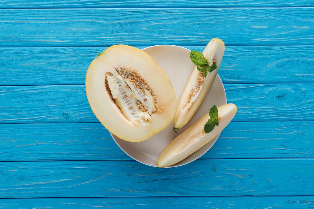 vue de dessus du melon sucré tranché mûr avec menthe sur plaque sur une surface en bois bleu
   - Photo, image