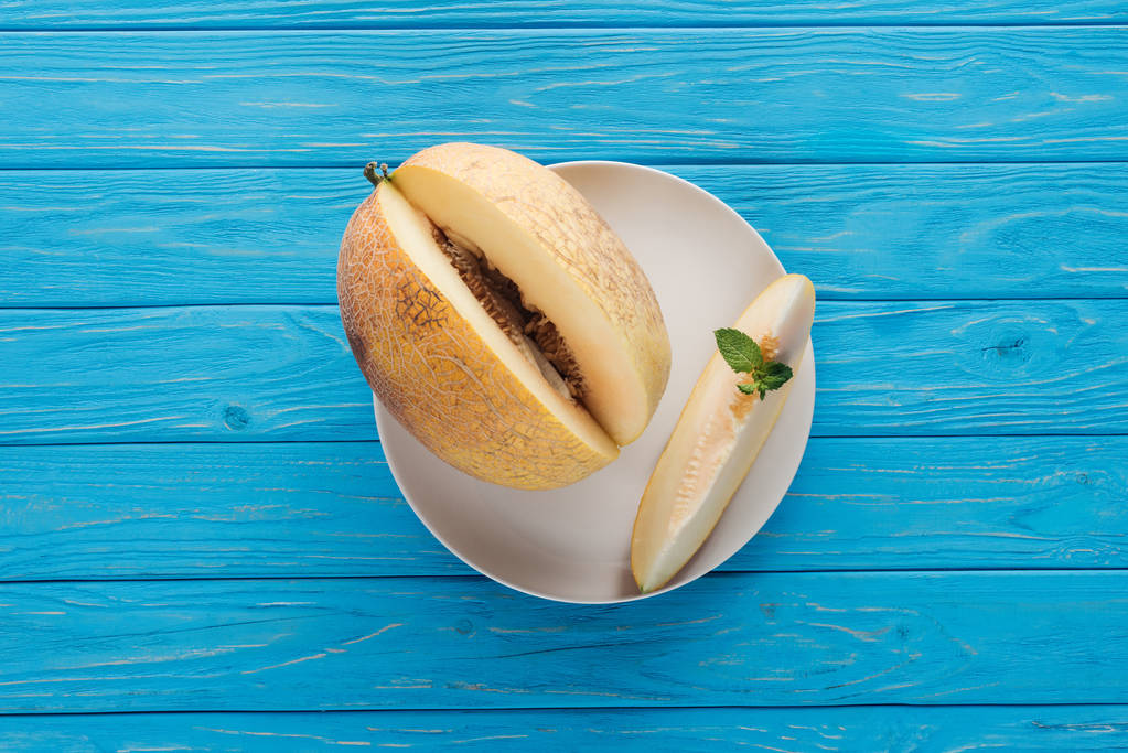 süße reife Melone mit Minze auf Teller auf blauer Holzoberfläche   - Foto, Bild