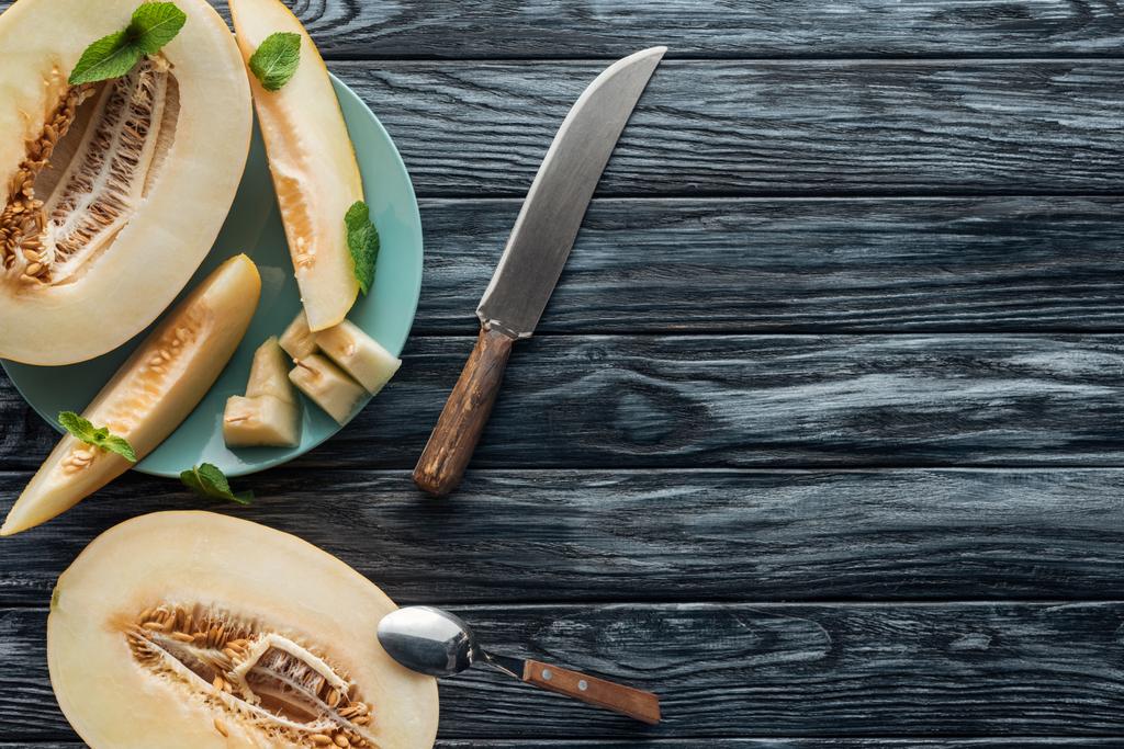 pohled shora sladký zralý meloun s lžíci a nůž na dřevěný povrch - Fotografie, Obrázek