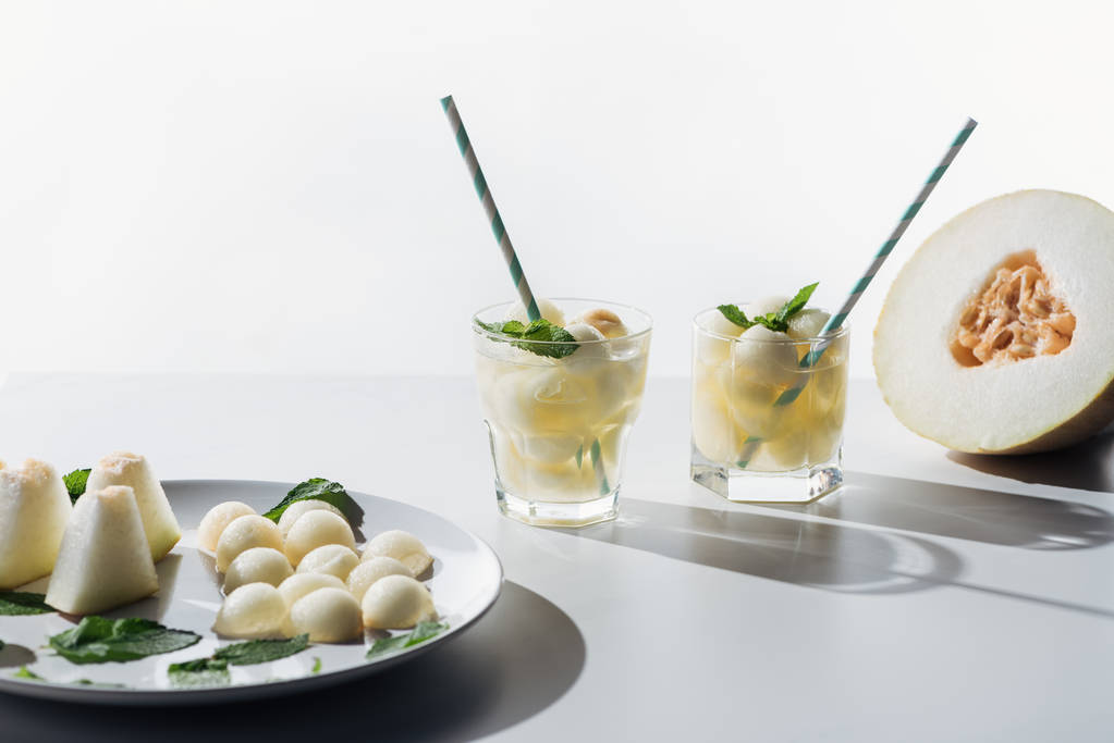 vista ravvicinata delle palline di melone dolce e bevanda rinfrescante con melone e menta in bicchieri su bianco
  - Foto, immagini