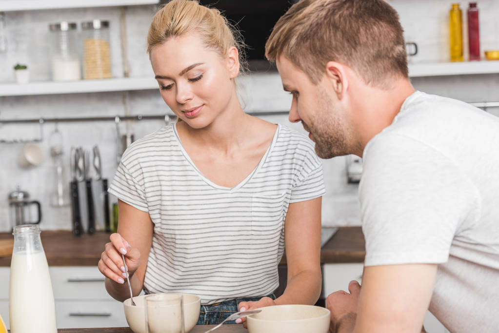 young couple in casual clothes having breakfast in kitchen  - Photo, Image
