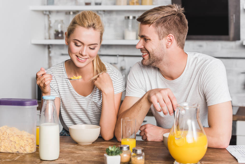 пара завтракает и ест кукурузные хлопья с молоком на кухне
 - Фото, изображение
