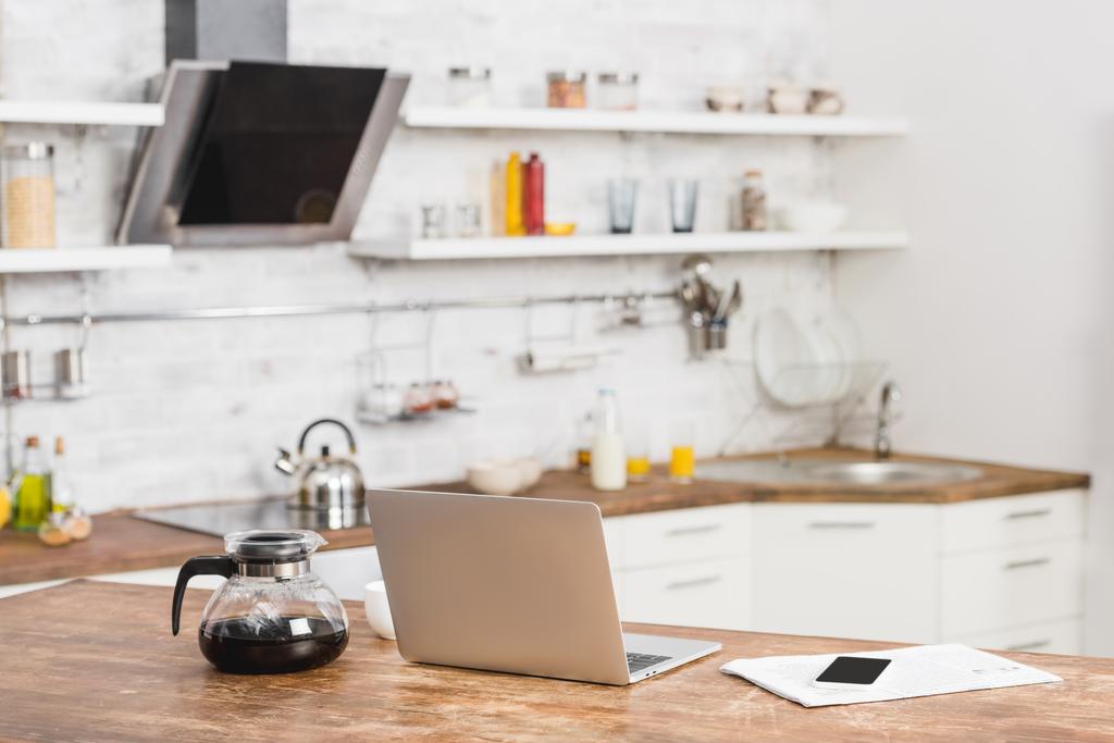 portátil, teléfono inteligente y cafetera en el mostrador de cocina
 - Foto, imagen