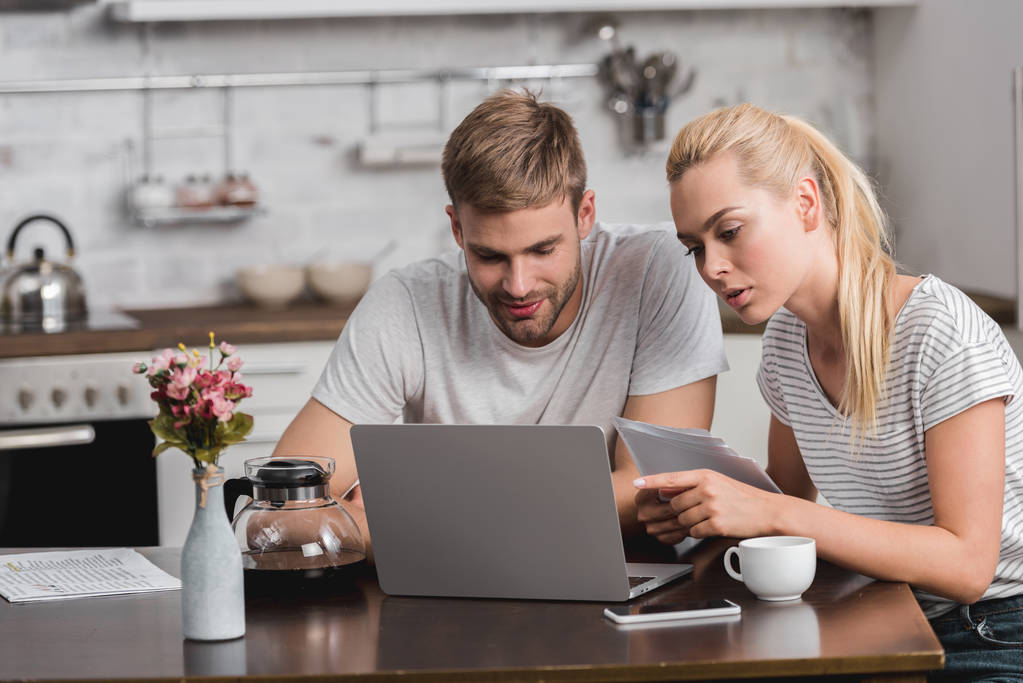 ζευγάρι συνεδρίαση και κοιτάζοντας το laptop στην κουζίνα - Φωτογραφία, εικόνα