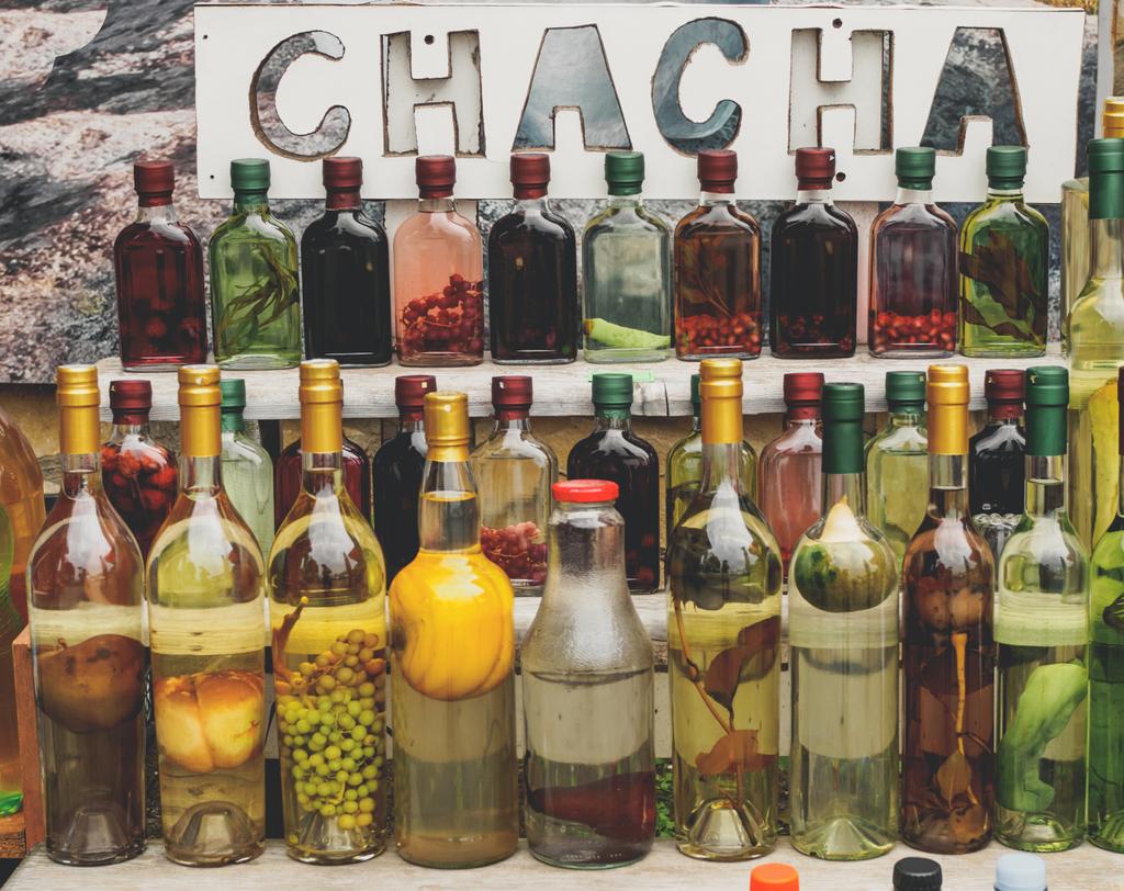 boisson alcoolisée géorgienne traditionnelle chacha en bouteilles avec différents fruits et herbes qui se vendent au marché
 - Photo, image
