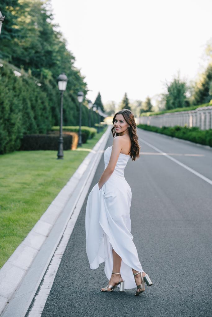 vista trasera de la novia feliz en vestido de novia caminando por el camino
 - Foto, imagen