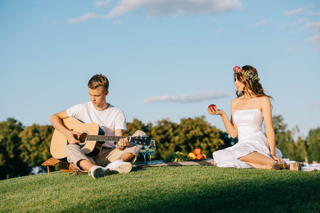 marié jouant sur la guitare acoustique pour mariée pendant le pique-nique romantique
 - Photo, image