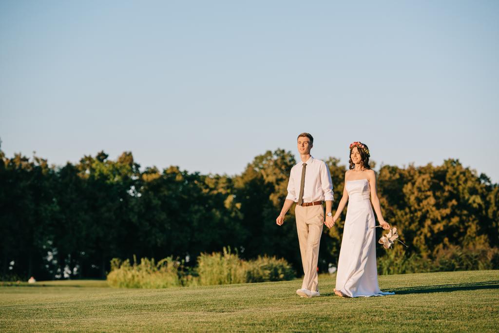 手を繋いで公園を一緒に歩いて美しい若い結婚カップル - 写真・画像