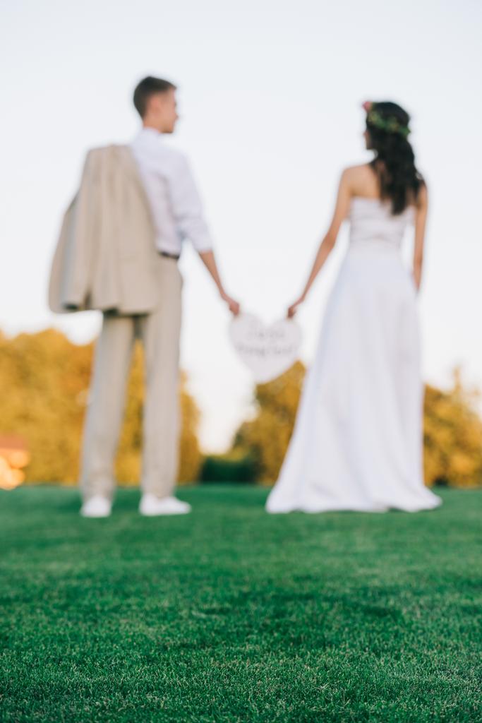 enfoque selectivo de la joven pareja de boda de pie juntos en el césped verde
  - Foto, Imagen