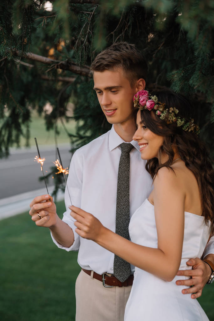 schöne glückliche junge Hochzeitspaar umarmt und hält Wunderkerzen - Foto, Bild