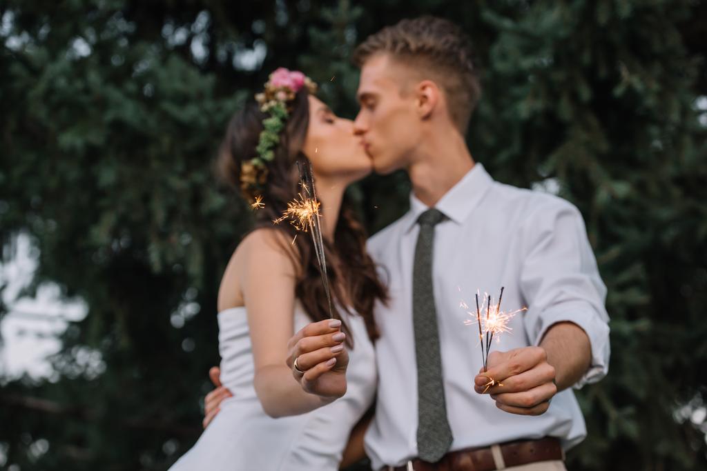 szelektív összpontosít, a boldog fiatal esküvői pár gazdaság csillagszórók, és csók - Fotó, kép