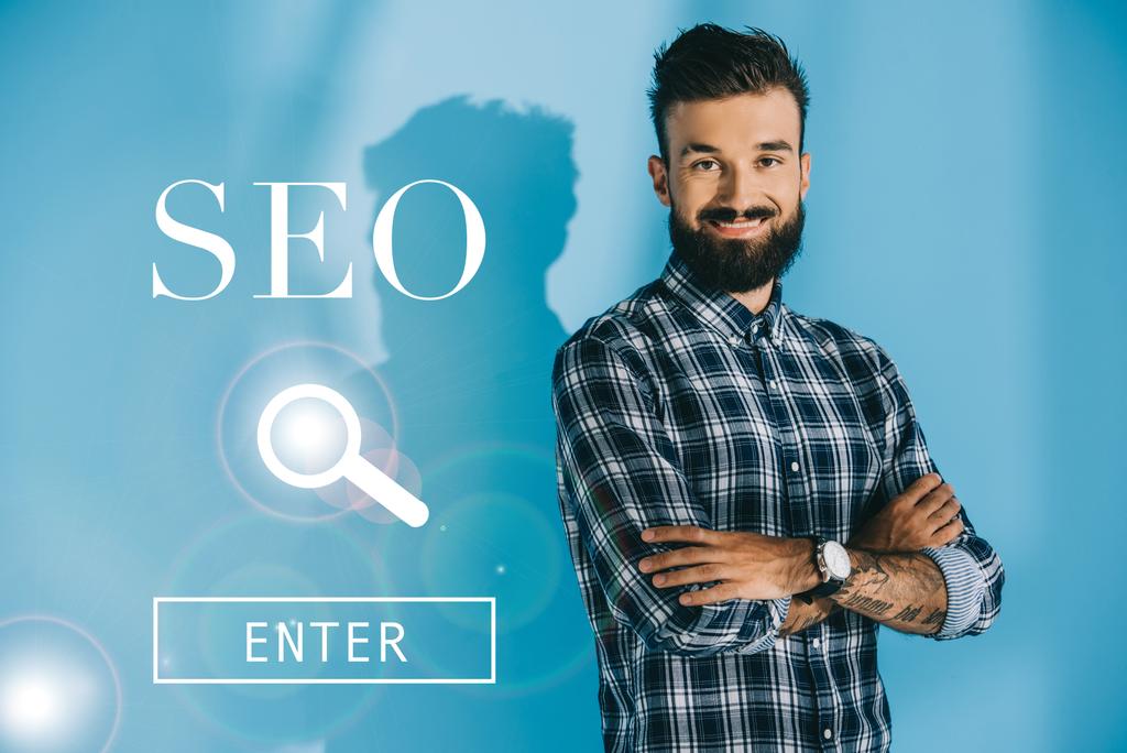 успішний бородатий розробник позує схрещеними руками, на синьому з пошуком SEO
 - Фото, зображення