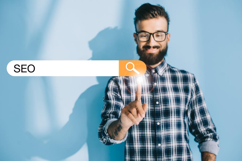 successful developer in checkered shirt pointing at SEO search bar - Photo, Image