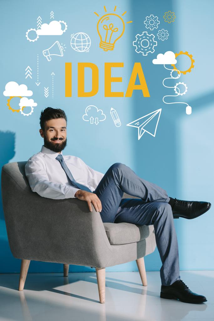 smiling businessman sitting in grey armchair, on blue with idea icons - Photo, Image