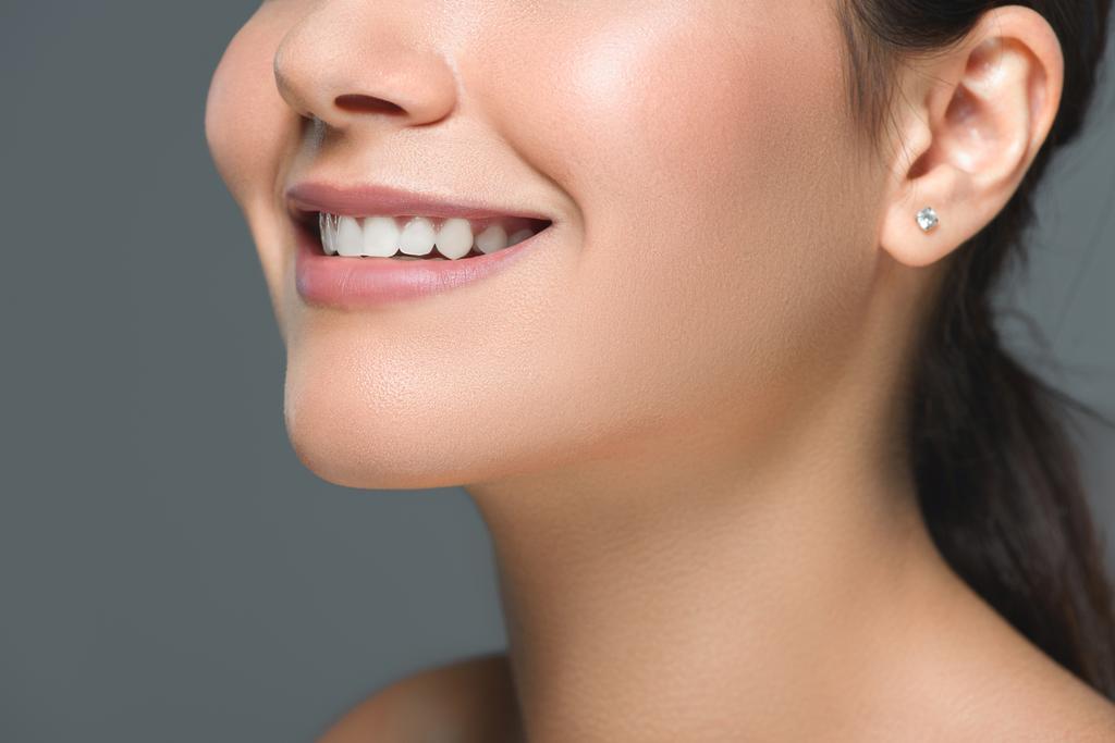 обрізаний знімок усміхненої жінки з красивими білими зубами ізольовані на сірому
 - Фото, зображення