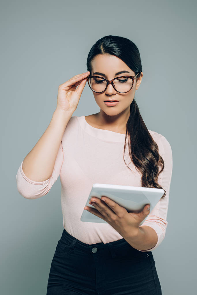 muotokuva brunette nainen silmälasit käyttäen digitaalista tabletti eristetty harmaa
 - Valokuva, kuva