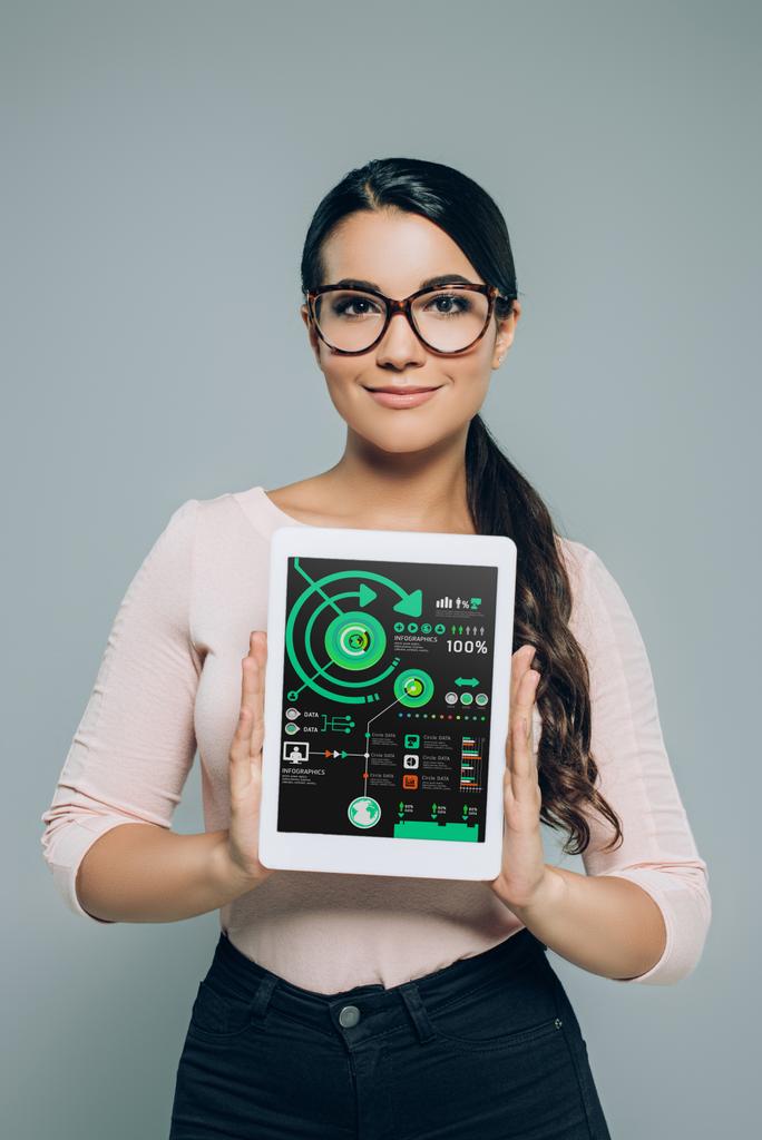 Frau zeigt digitales Tablet mit Business-Infografik, isoliert auf grau - Foto, Bild