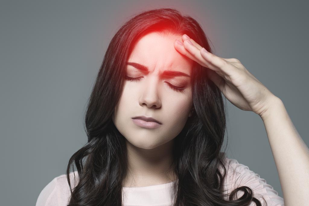 zieke vrouw die lijden aan hoofdpijn, met rode pijnlijke punt, geïsoleerd op grijs - Foto, afbeelding