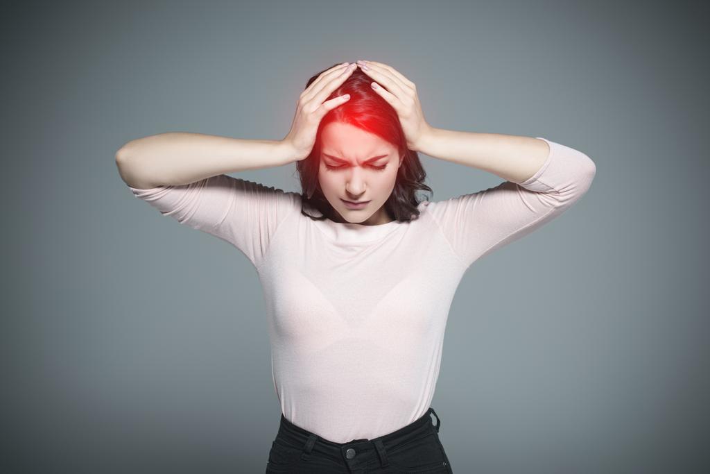 mulher com dor de cabeça e ponto doloroso vermelho na cabeça, isolado em cinza
 - Foto, Imagem