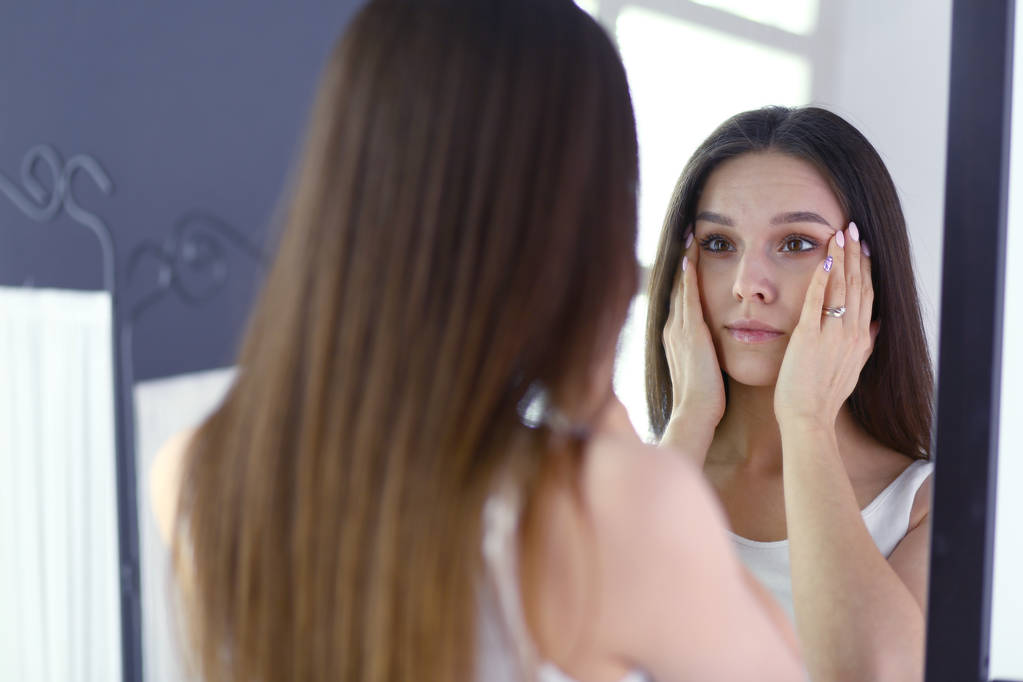 Mujer joven mirándose a sí misma reflejo en el espejo en casa
. - Foto, Imagen