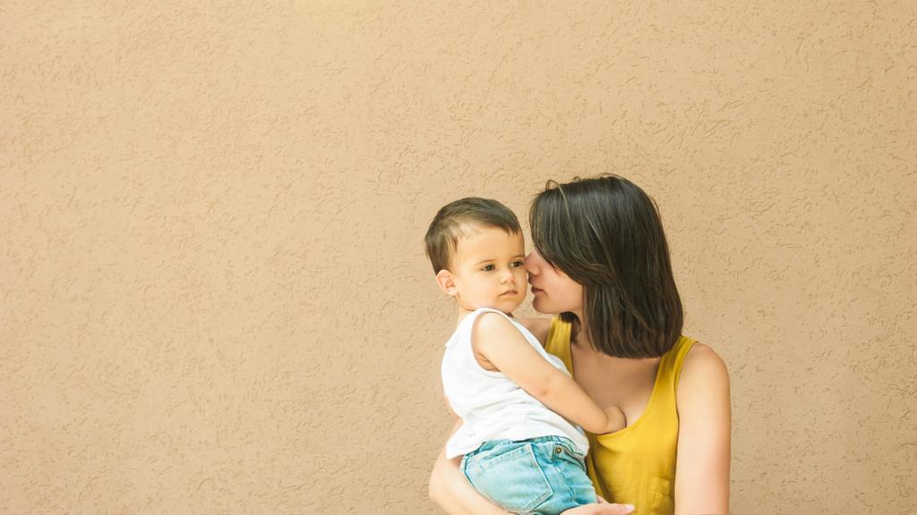 madre toccante guancia figlio sulla strada vicino alla parete beige
 - Foto, immagini