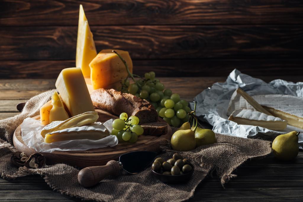 erityyppiset juustot, viinirypäleet ja päärynät pöydällä
 - Valokuva, kuva