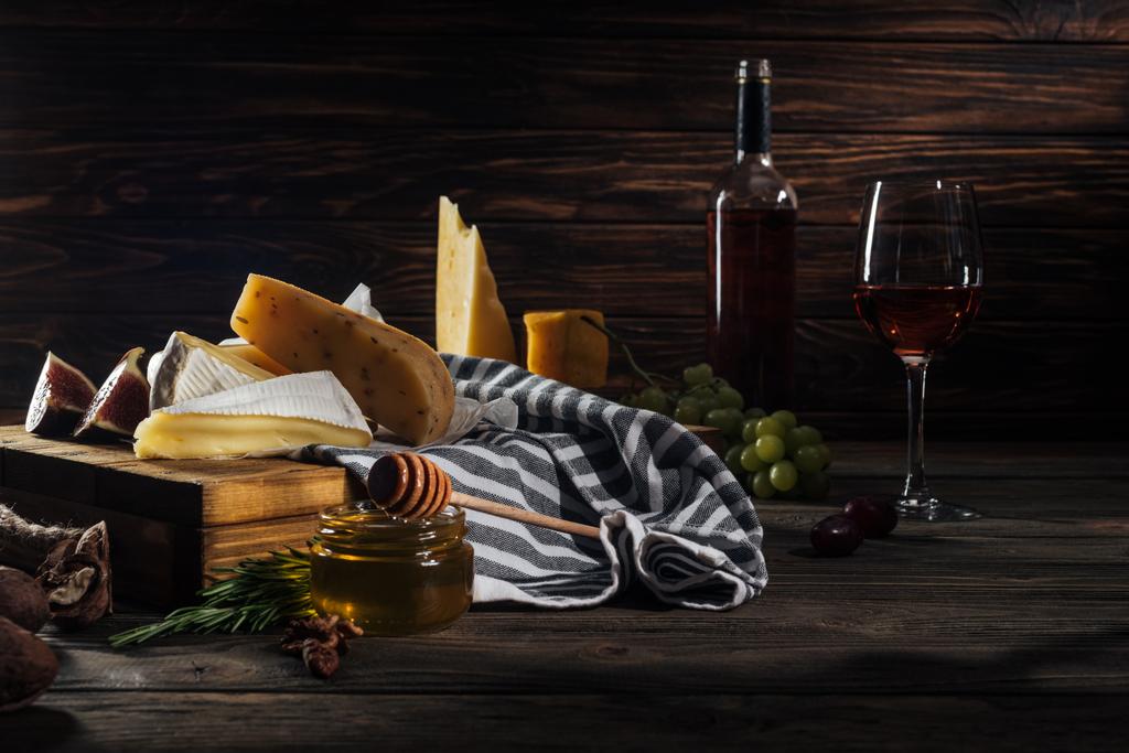 different types of cheeses, honey with stick and wine on table - Photo, Image