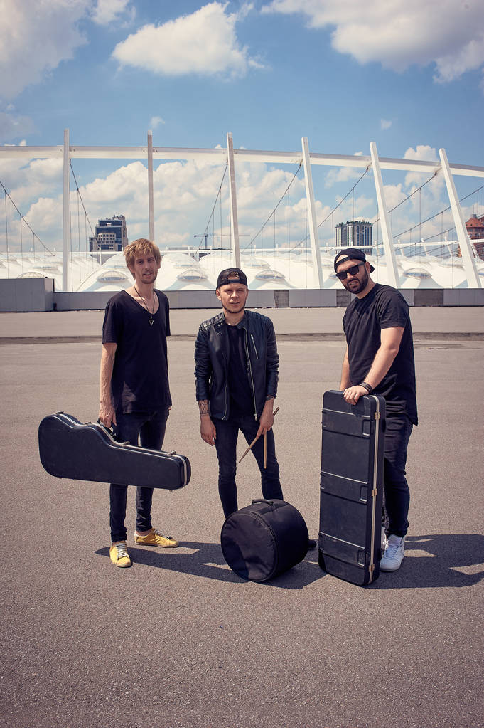 rock music band with musical instruments in cases standing on street - Photo, Image