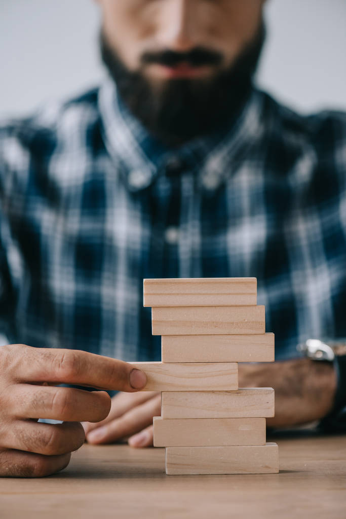 bijgesneden beeld van de mens spelen met houten blokken tower spel - Foto, afbeelding