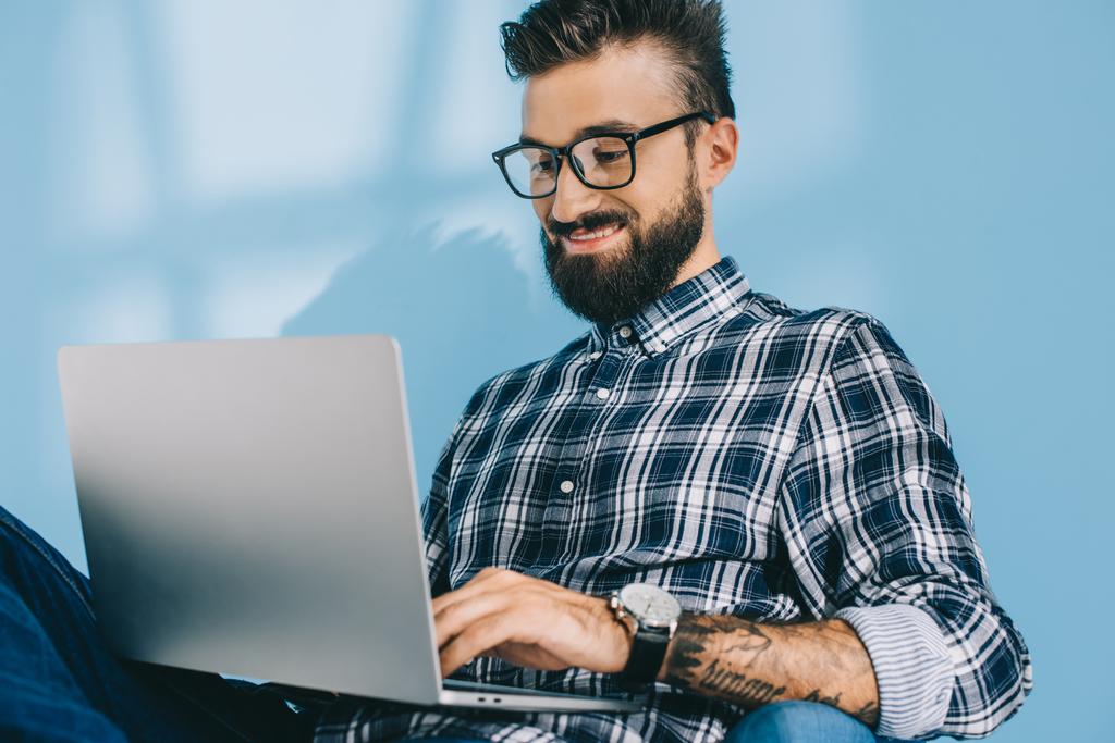 hombre sonriente guapo usando el ordenador portátil, en azul
 - Foto, Imagen