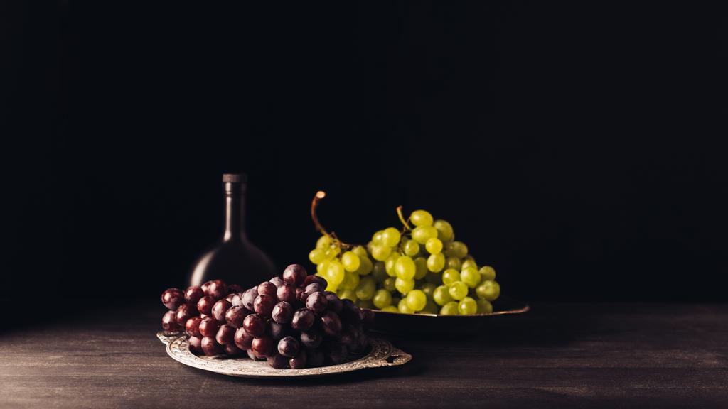 friss érett piros és fehér szőlőt vintage lemezek és üveg bort a fából készült asztal, fekete   - Fotó, kép