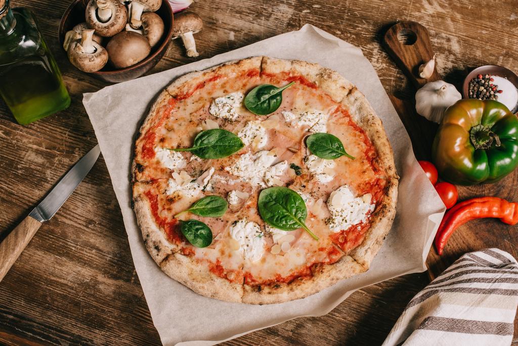 vista dall'alto della pizza, degli ingredienti e del coltello italiano su un tavolo di legno
 - Foto, immagini