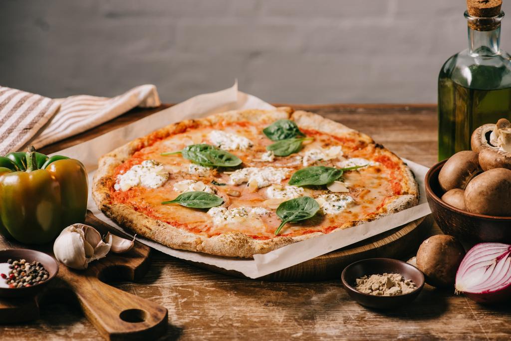 close up view of delicious italian pizza and ingredients on wooden surface - Photo, Image