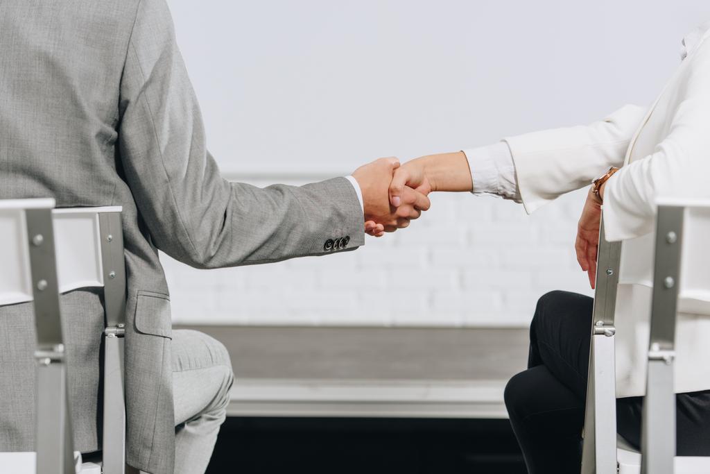 cropped image of businessman and businesswoman shaking hands during business training in hub - Photo, Image