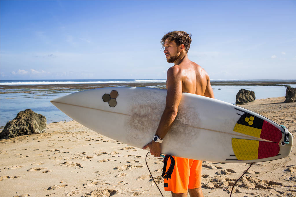 vista laterale del giovane surfista con tavola da surf in piedi sulla spiaggia sabbiosa durante la giornata estiva
 - Foto, immagini