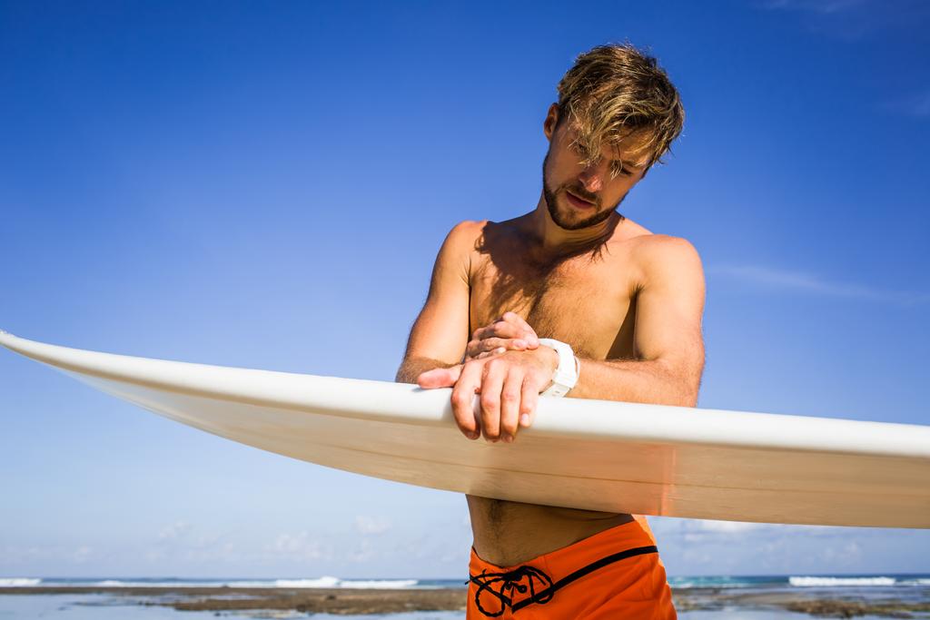 atleta desportista com prancha de surf verificando o tempo na costa no dia de verão
 - Foto, Imagem