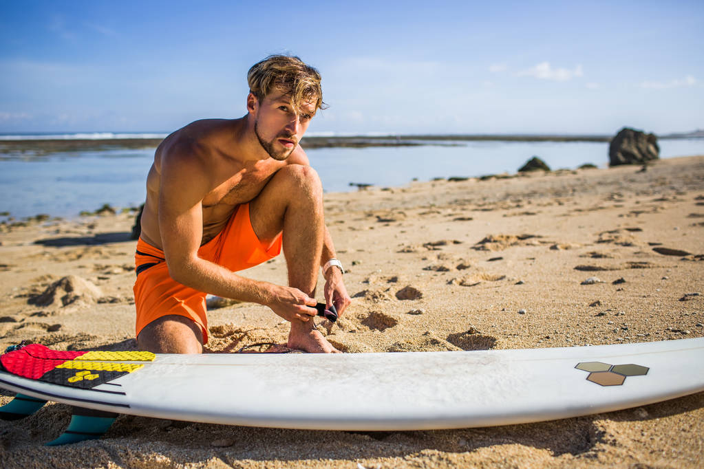jeune sportif se préparant pour le surf sur la plage de sable
 - Photo, image